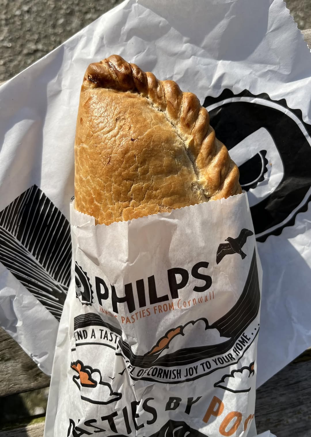 Cornish pasty in a paper bag from Philps Bakery in Marazion