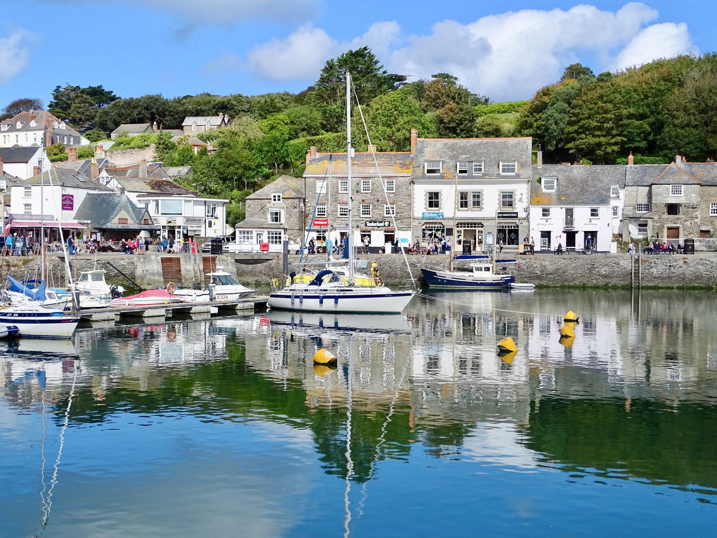 Boats moored in Padstow harbour on the Camel Estuary with waterside shops and cafés along the quay