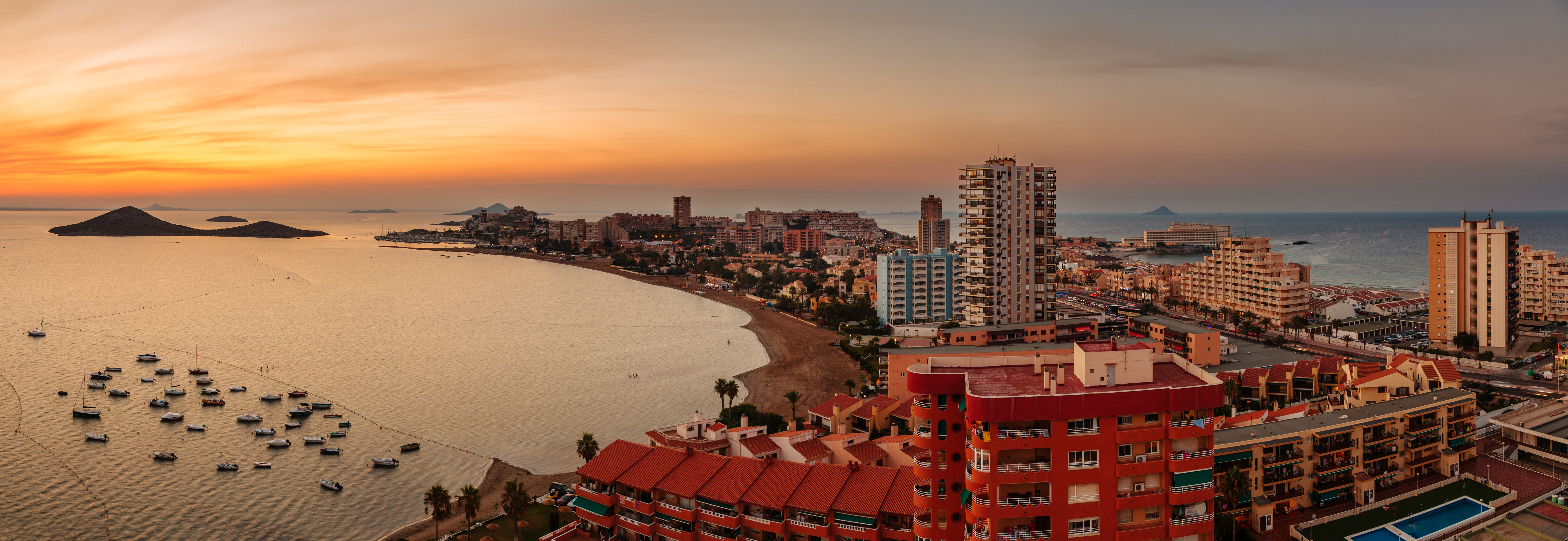La Manga del Mar Menor skyline at sunset, with coastal apartments, boats and calm water along Murcia&rsquo;s coastline.