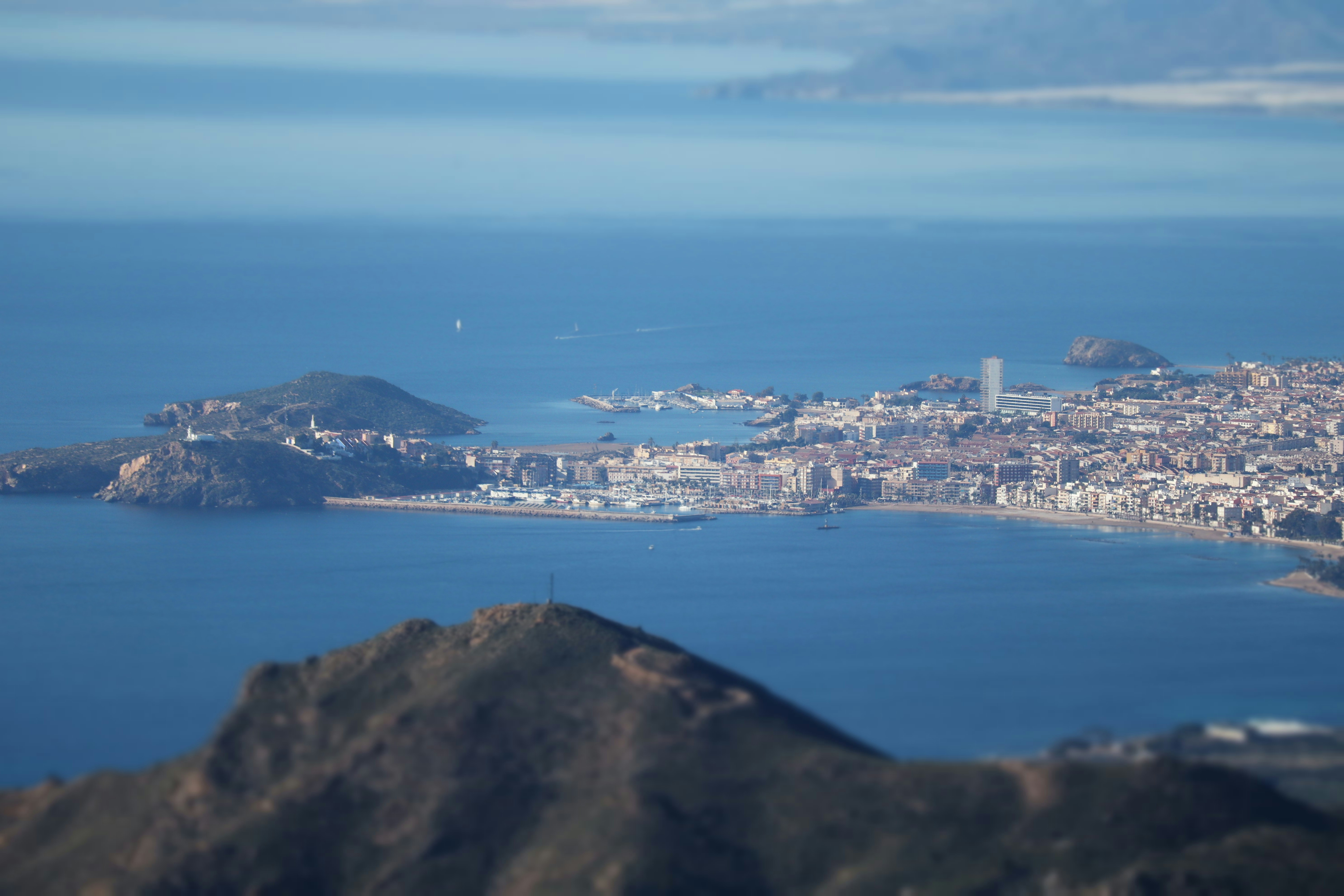 View over Mazarr&oacute;n and the Costa C&aacute;lida coastline, with blue sea, rocky hills and the town in the distance.