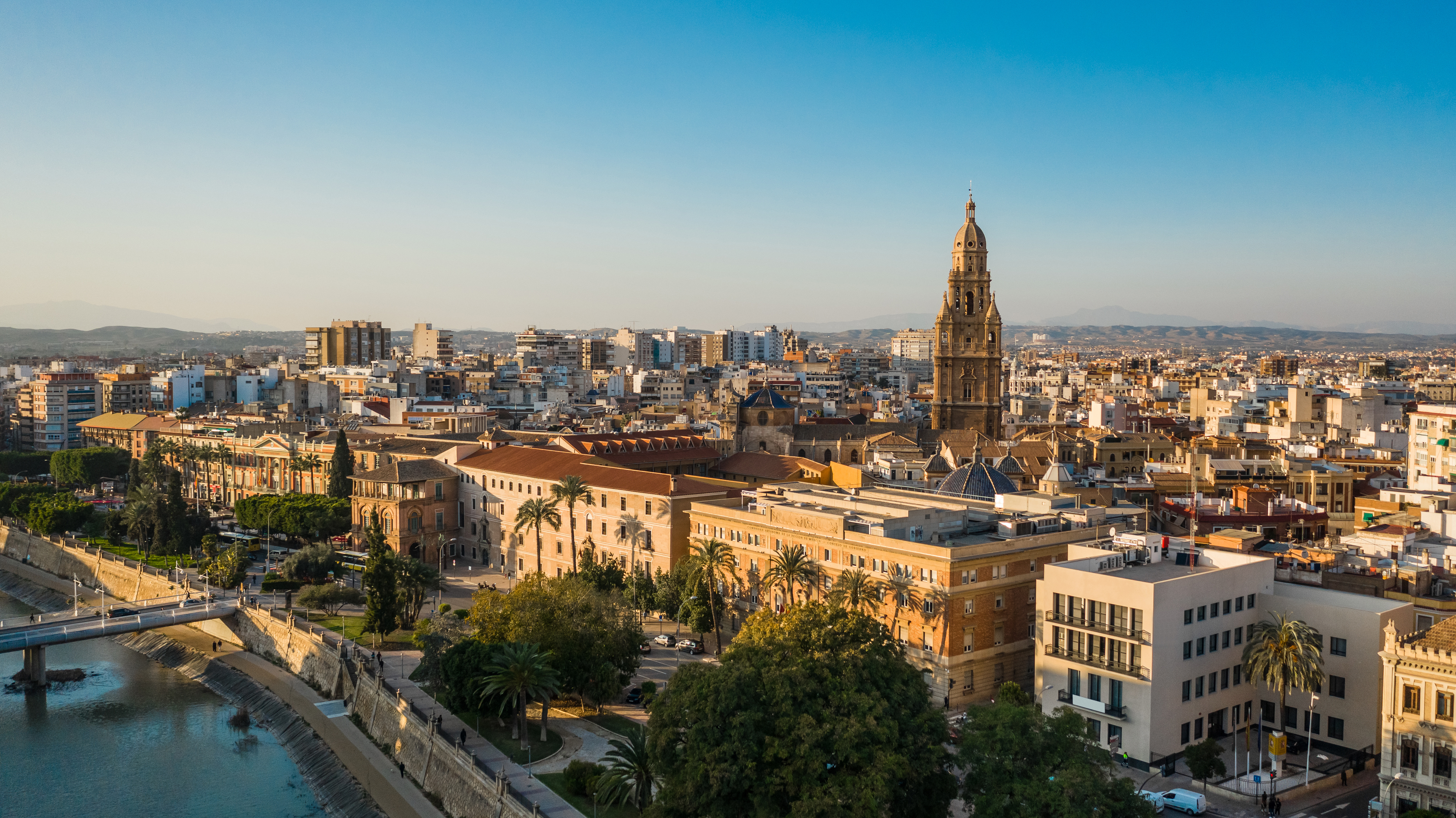 View over Murcia city centre with the cathedral tower, Segura River and surrounding historic buildings in warm evening light