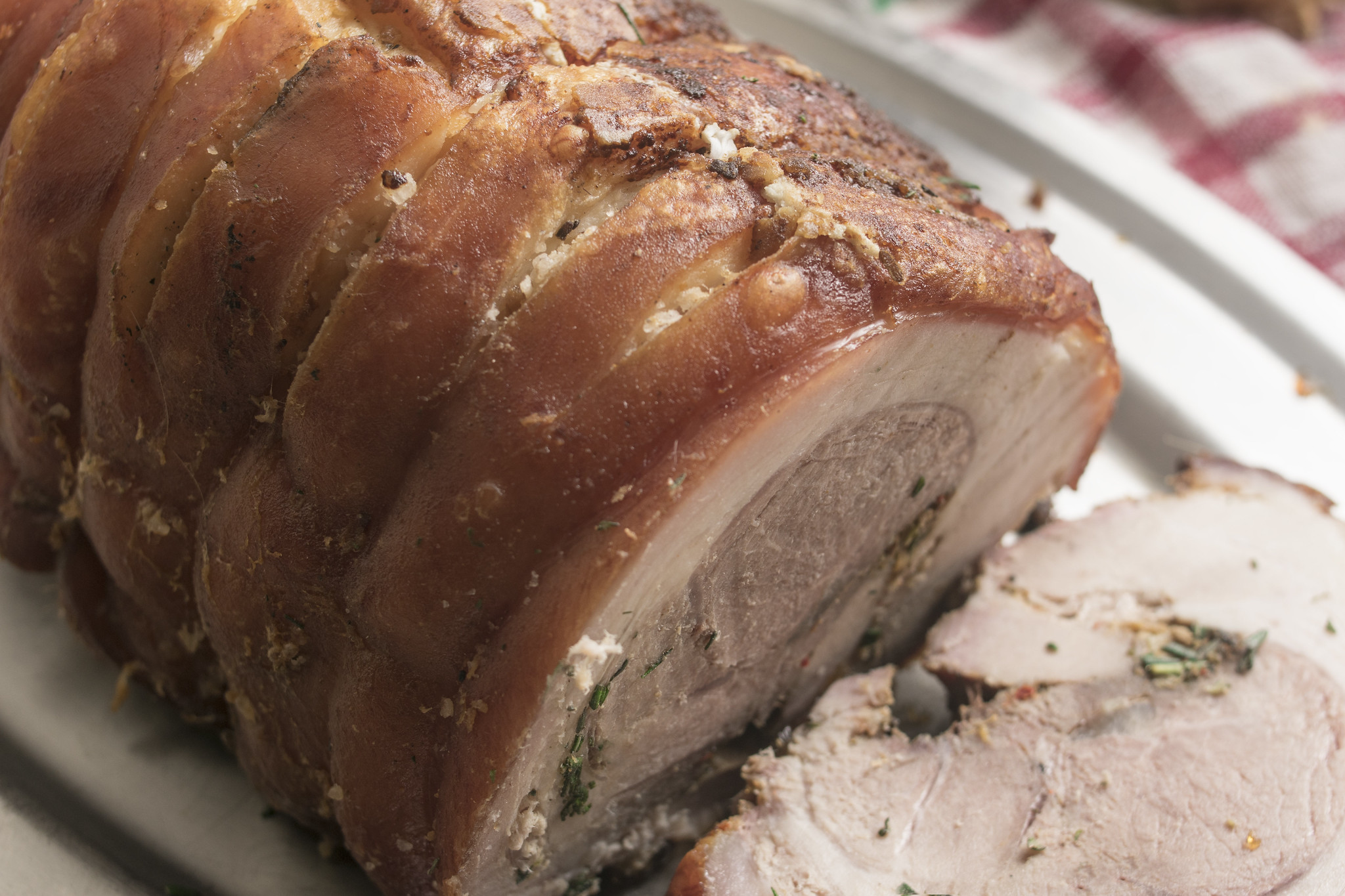 Sliced porchetta with crisp golden skin, tender pork and herby fennel and rosemary filling