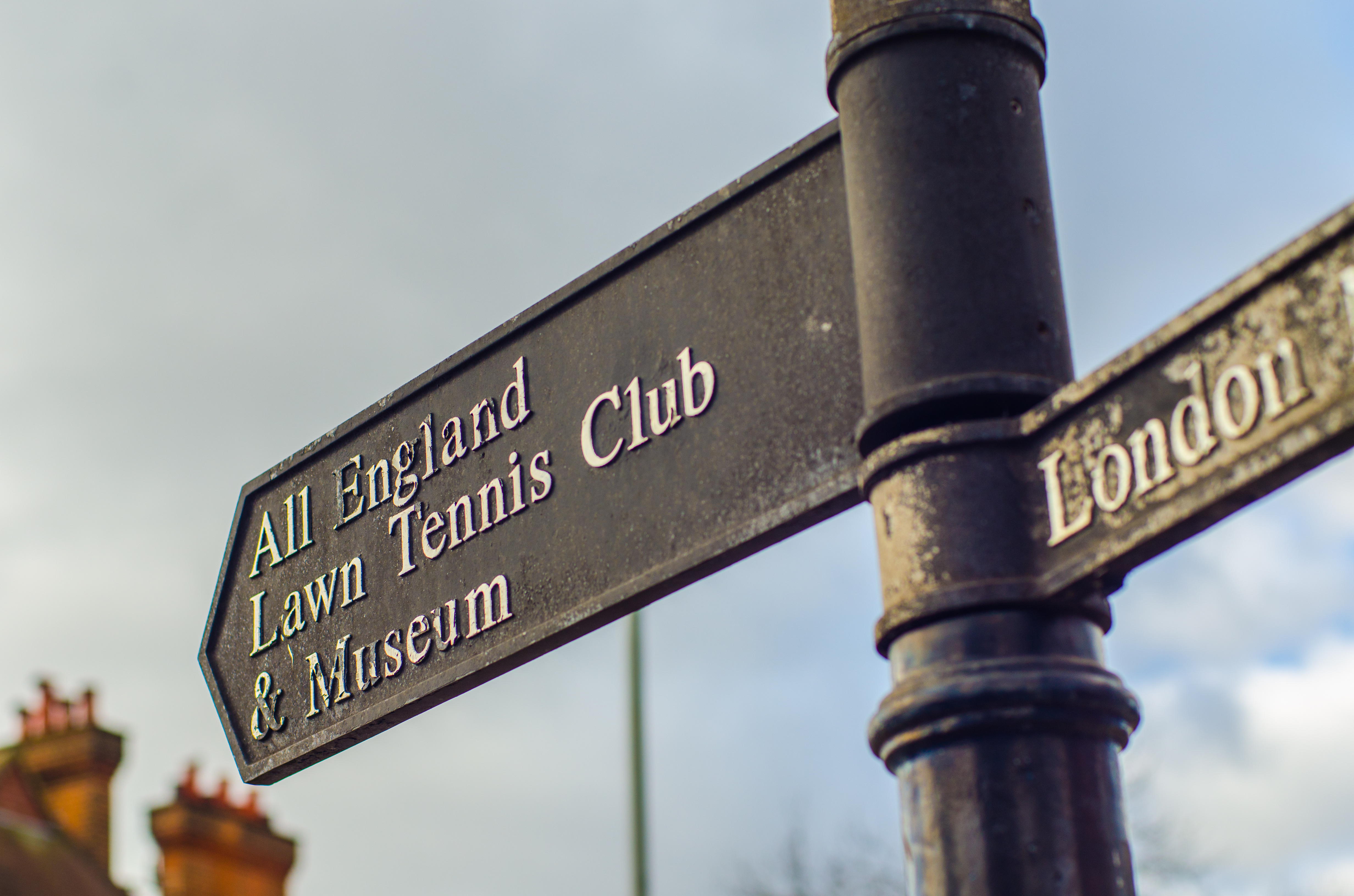 Black directional street sign pointing towards the All England Lawn Tennis Club and Museum in Wimbledon, London.