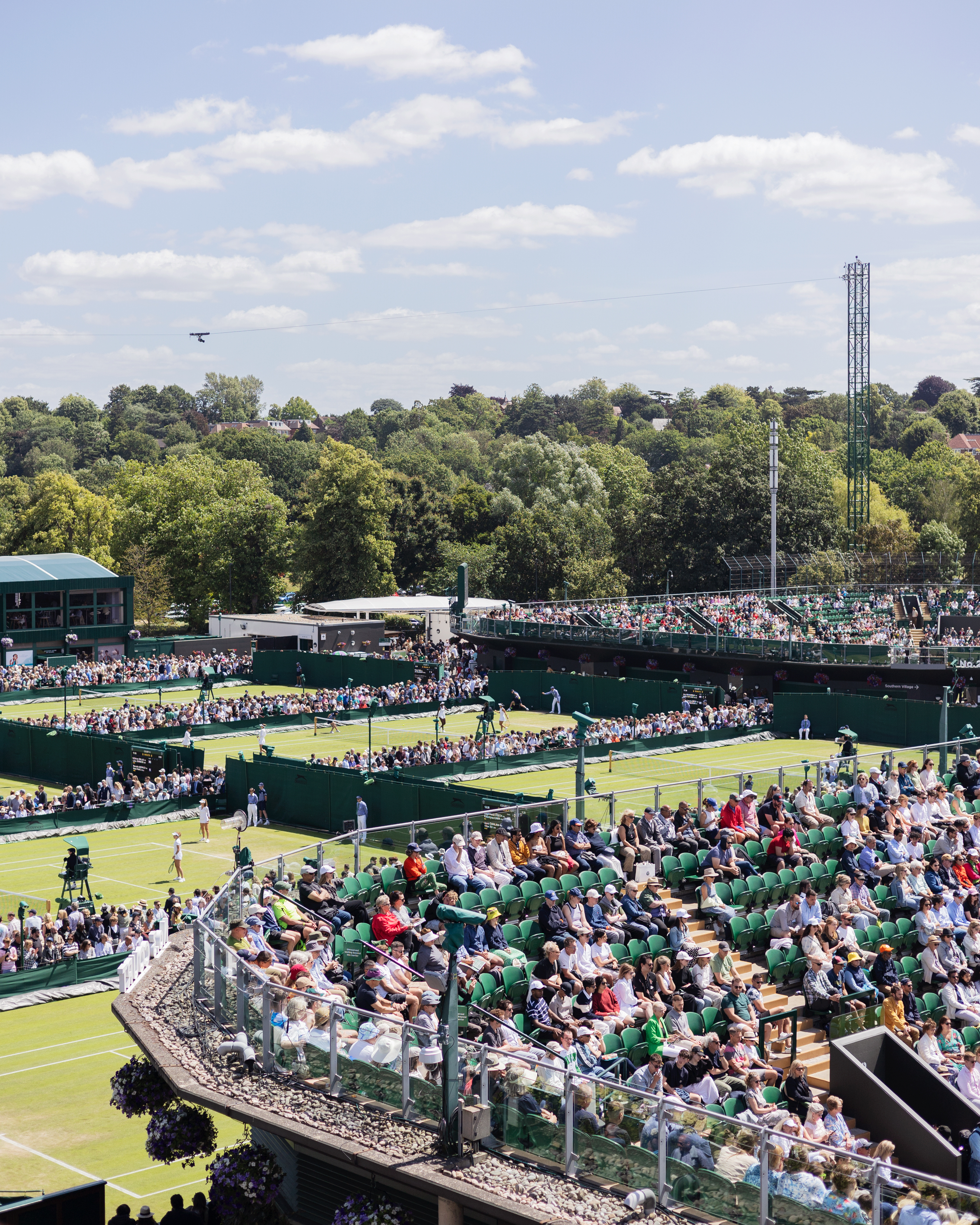 Crowds watching tennis across the grass courts at Wimbledon during the Championships in London.