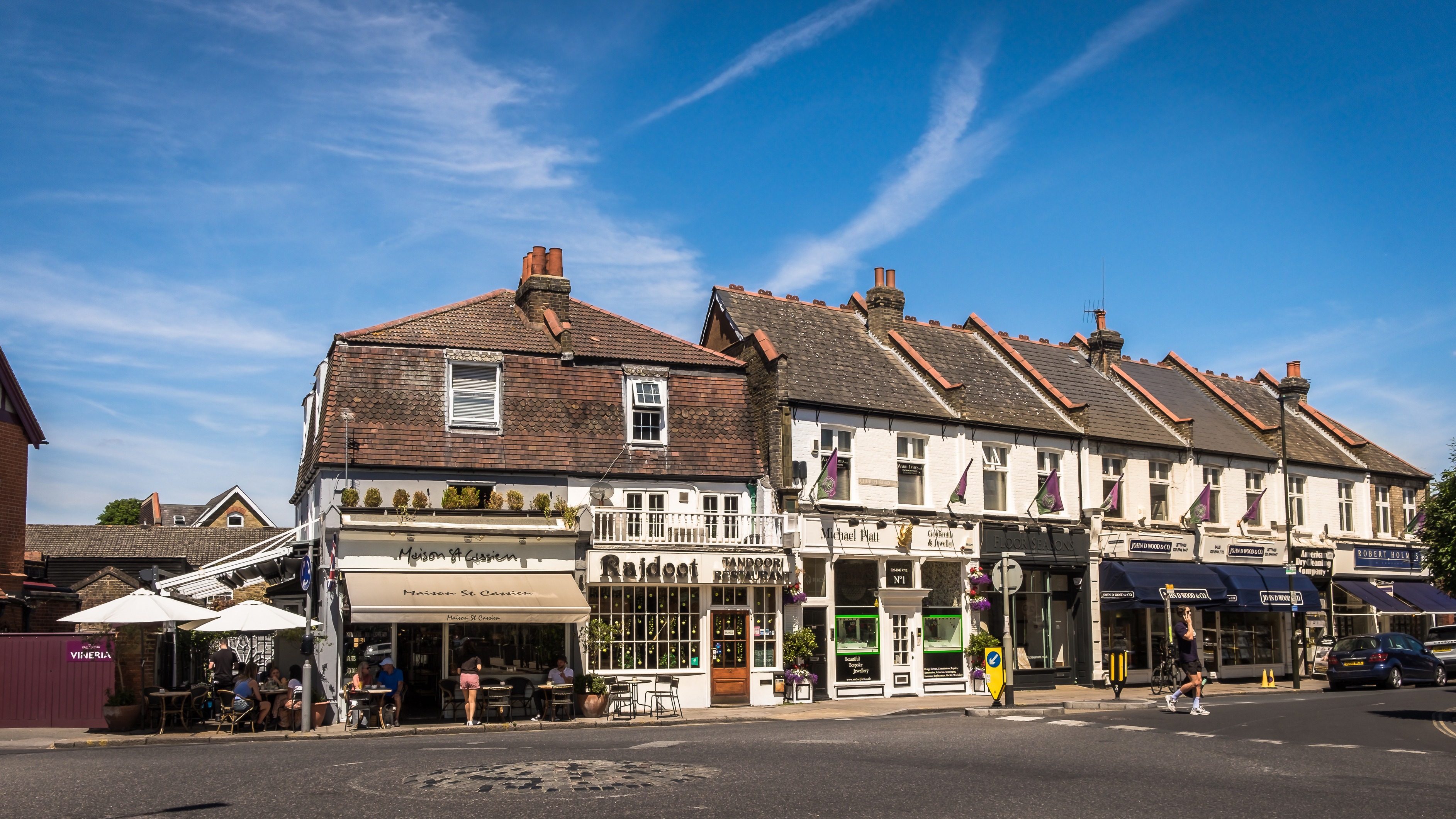 A row of shops, cafés and restaurants in Wimbledon Village, showing the characterful atmosphere of one of the most appealing areas to stay in Wimbledon.
