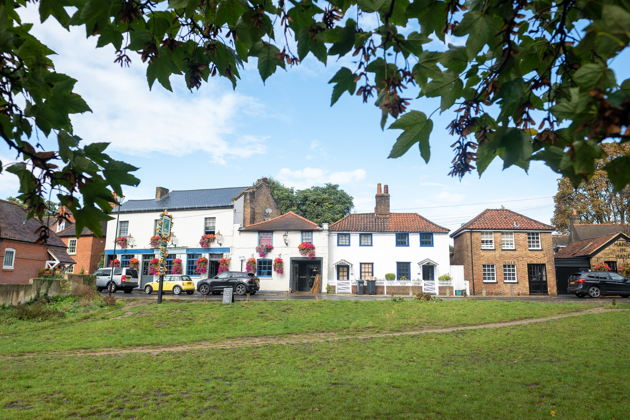 Traditional pubs and village buildings beside a green open space in Wimbledon, London.